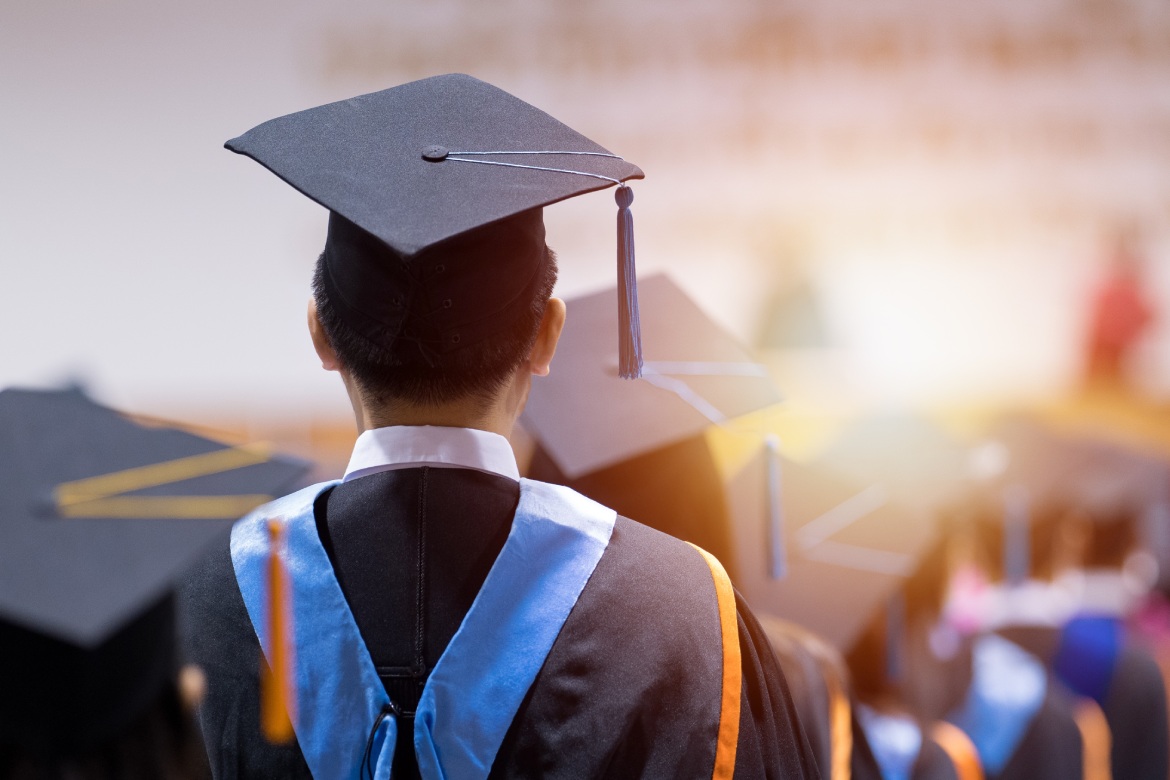 Rear view of university graduates wearing graduation gown and cap in the commencement day