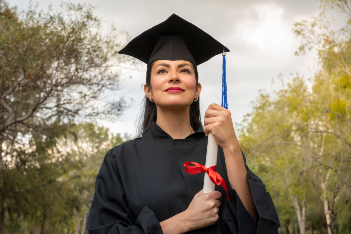 primer plano estudiante latina mirando al frente sosteniendo su titulo el dia de su graduacion. concepto de graduacion