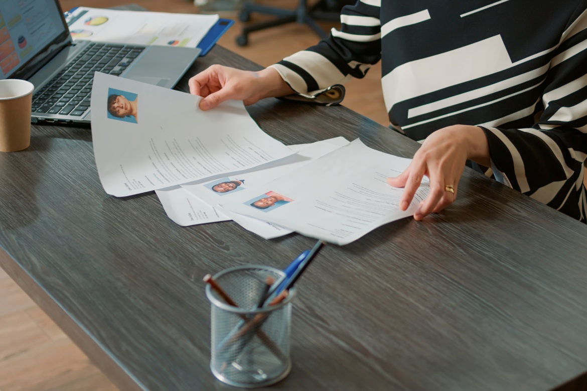 Empleada de RRHH mirando el currículum vitae para contratar candidatos, analizando información antes de la entrevista de trabajo. Mujer utilizando documentos de experiencia para hacer una oferta de trabajo y contratar candidatos. Primer plano.