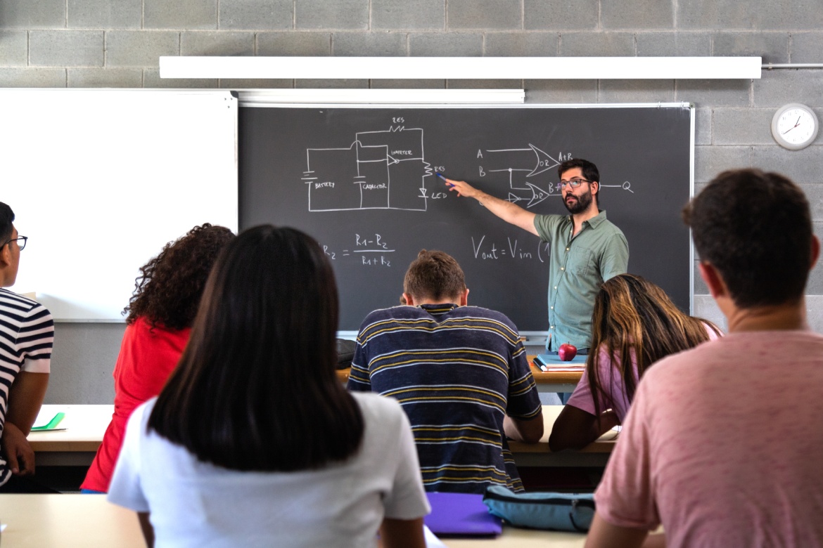 Male caucasian teacher explaining electronics and physics to multiracial high school students.