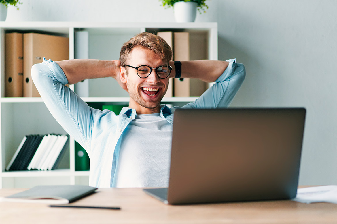 young man smiling in front computer.